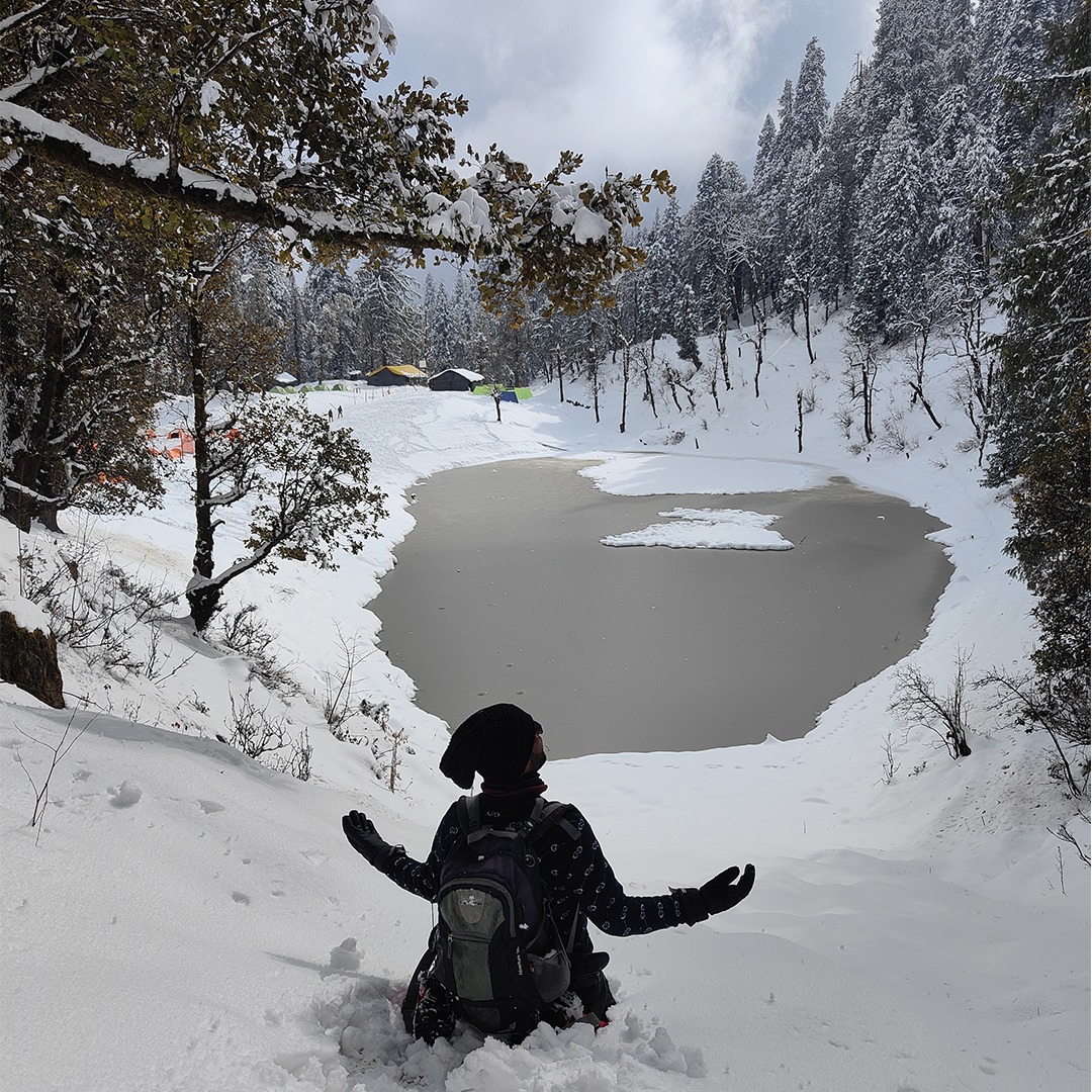 Frozen Juda Ka Talab during Kedarkantha trek surrounded by dense forest