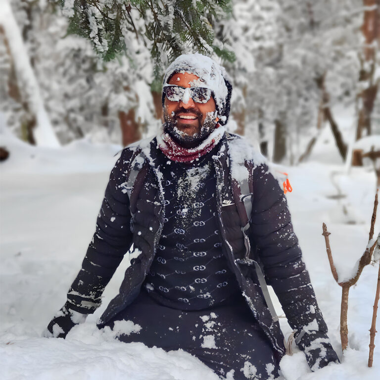 Trekking through deep snow on the Kedarkantha Trek in Uttarakhand.