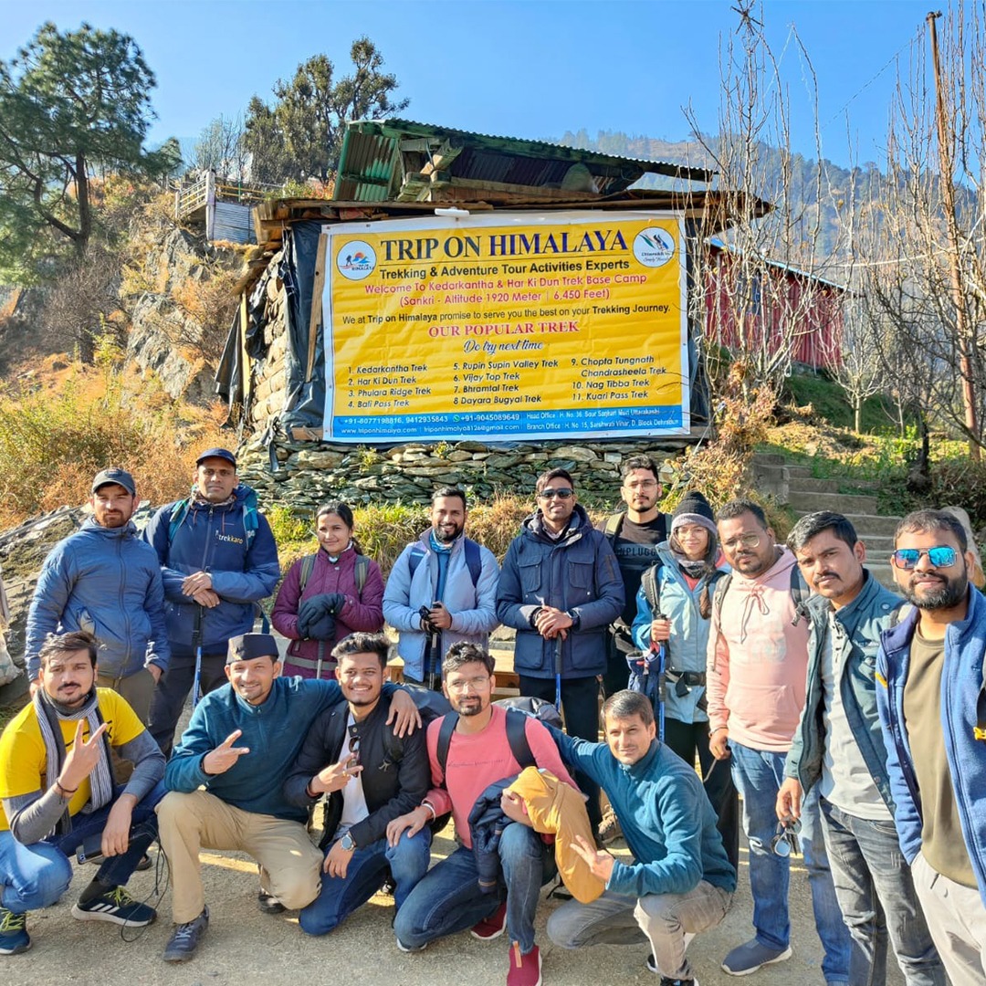 Group of trekkers posing at Sankri Base Camp with the majestic Himalayan mountains in the background